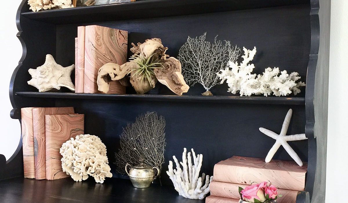 We specified a navy painted hutch in this California coastal home on which we put shells and branches found at the local beach alongside paper wrapped books. Design by 1 Chic Retreat
