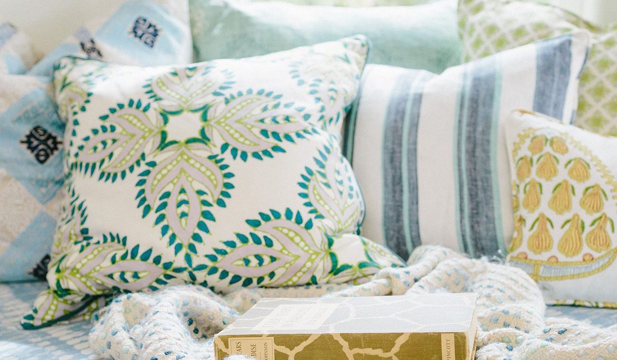 The blue and green striped pillow contrasts nicely with the curvy designs of the two adjoining pillows. Design by 1 Chic Retreat